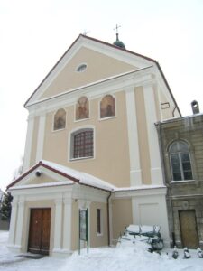 kościół z widocznymi na elewacji frontowej malowidłami. Zdjęcie wykonano okresie zimowym